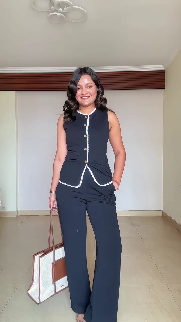 Chic Minimalism: Sleeveless Black Top with White Trim Paired with Trousers